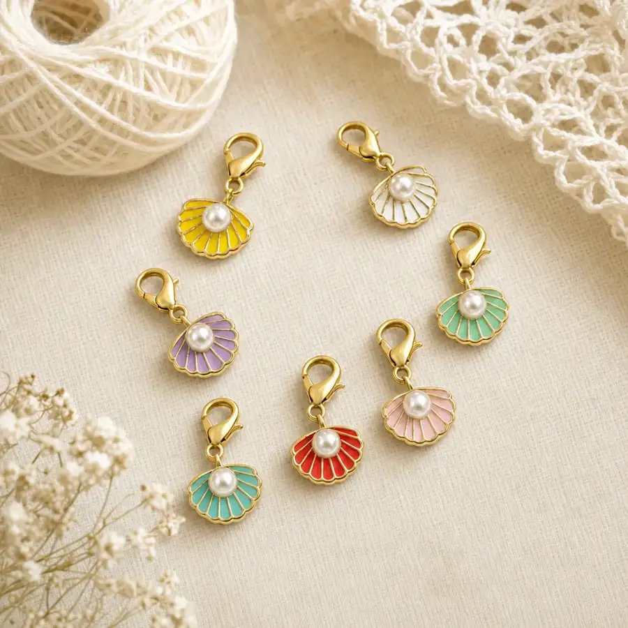 Pearl shell charm stitch markers styled as a gift on cream linen with yarn