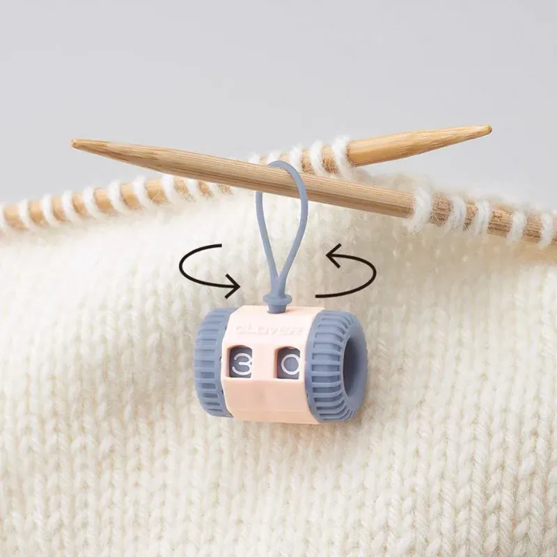 On-needle knitting row counter with rotating number dials, mounted on a wooden needle