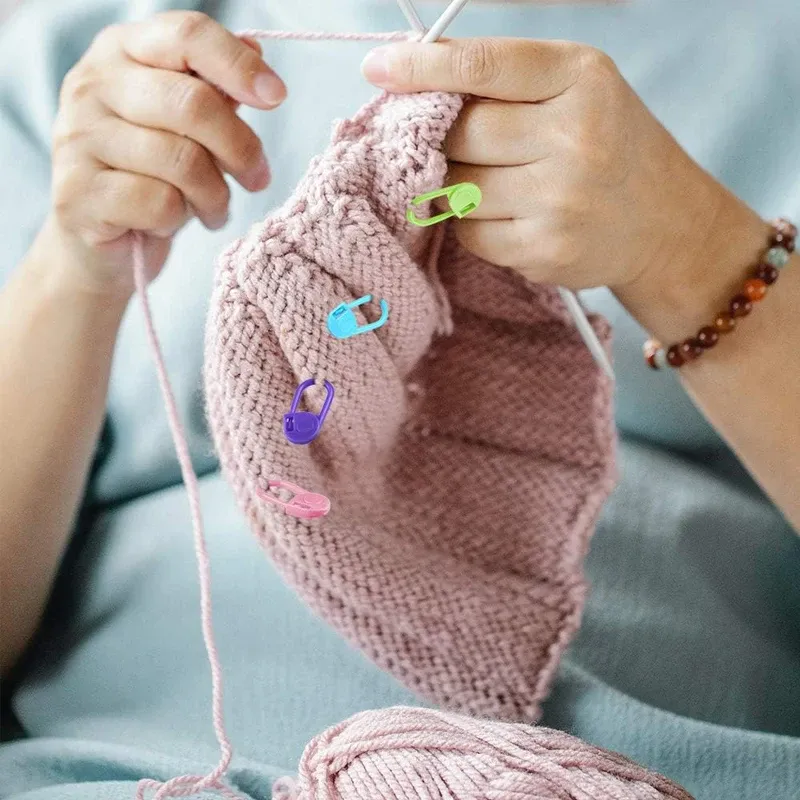 Knitter using locking stitch markers on a work-in-progress sweater